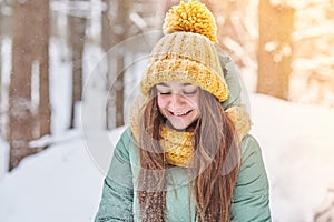 Beautiful young girl in knitted hat on winter forest background