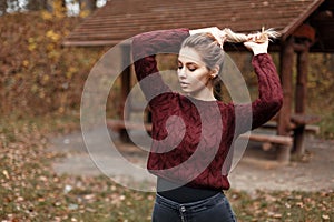 Beautiful young girl in knitted sweater on nature in autumn day.