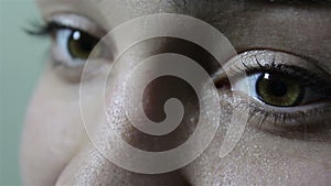 A beautiful young girl with large green-brown eyes looks coquettishly at the camera.