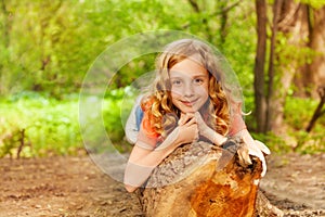 Beautiful young girl laying on the log in forest