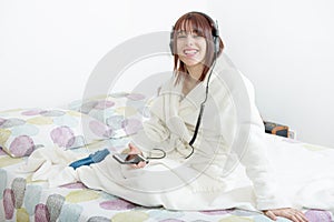 Beautiful young girl listening to music in her bed