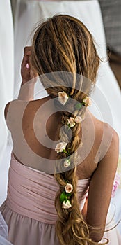 Beautiful young girl with long hair flowers the tenderness of the mystery in a braid steed back