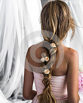 Beautiful young girl with long hair flowers the tenderness of the mystery in a braid steed back