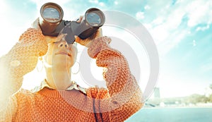 Beautiful Young Girl Looking Through Binoculars At The Sea On A Bright Sunny Day. Travel Holidays Journey Concept