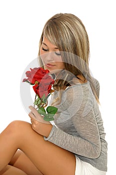 Beautiful young girl looking at red rose