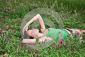 Beautiful young girl lying on green grass