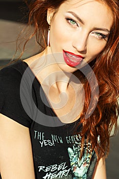 Beautiful young girl with makeup with enticing the big red lips and long hair in a Sunny summer day sitting on the street