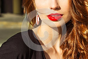 Beautiful young girl with makeup with enticing the big red lips and long hair in a Sunny summer day sitting on the street