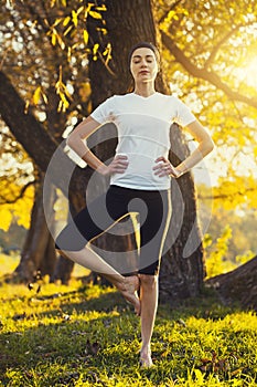 Beautiful young girl meditating in autumn park