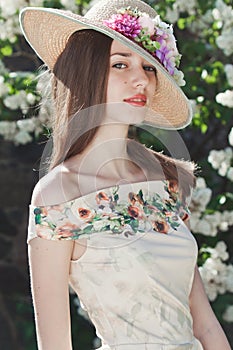 Beautiful young girl model posing near blooming lilacs at spring