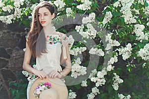 Beautiful young girl model posing near blooming lilacs at spring