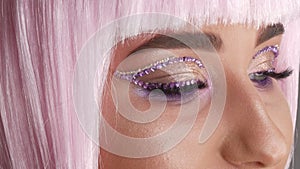 Beautiful young girl model posing in a pink short bob wig, rhinestones on her eyes and stylish pink makeup, high fashion