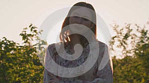 Beautiful young girl model posing in sunset beams in the country, hugging herself. Natural beauty. Handheld video