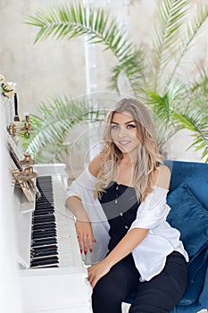 Beautiful young girl musician near a white piano