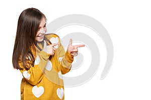 Beautiful young girl in mustard yellow sweater llaughing while pointing to the side. Waist up studio shot on white background.