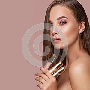 Beautiful young girl with natural nude make-up with cosmetic in hands. Beauty face.