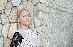 Beautiful young girl near a stone wall