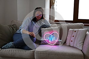Beautiful young  girl with neon signs. Neon sign pink heart. Trendy style. Valentine day