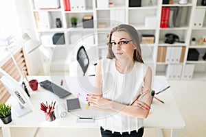 Beautiful young girl in an office is standing near a table.