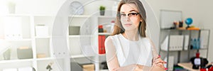 Beautiful young girl in an office is standing near a table.