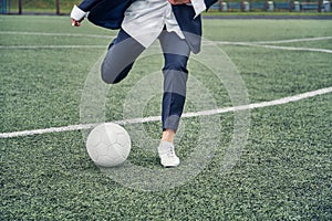 Beautiful young girl in office suit plays soccer