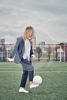 Beautiful young girl in office suit plays soccer