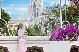 Beautiful young girl on the Ortiz Bridge eating a mango. On background the famous gothic church of La Ermita built on 1602 in the photo