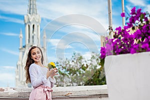 Beautiful young girl on the Ortiz Bridge eating a mango. On background the famous gothic church of La Ermita built on 1602 in the photo