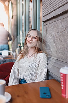 Beautiful young girl in outdoor cafe smiles