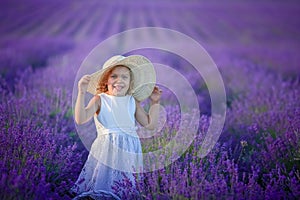 A Beautiful young girl outdoors portrait. kid in hat with basket flowers harvesting in lavender field Provence, at