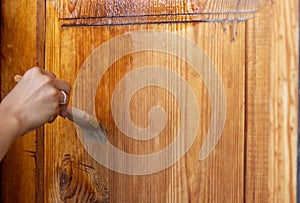 Beautiful young girl paints a wooden door. Summer work in the garden