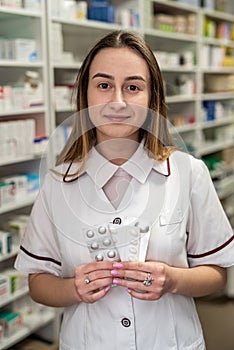 beautiful young girl pharmacist smiling in a dressing gown at her pharmacy.