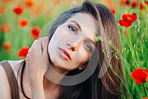 Beautiful young girl in poppy fields at sunset.