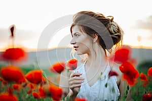 Beautiful young girl in poppy fields at sunset. Beautiful nature.