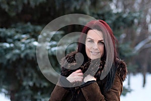 Beautiful young girl portrait on winter background. Charming young lady walking in a winter forest. Attractive woman posing.