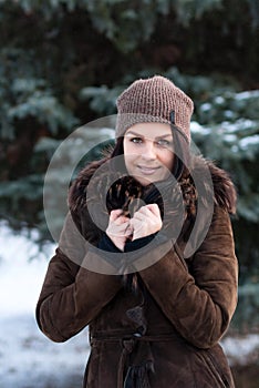 Beautiful young girl portrait on winter background. Charming young lady walking in a winter forest. Attractive woman posing.