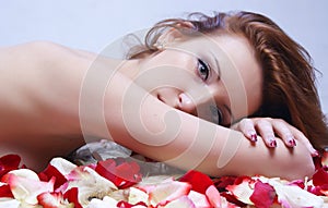 Beautiful young girl posing against the background of rose petal