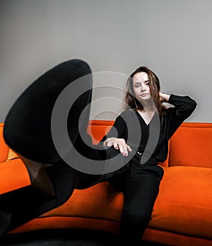 Beautiful young girl posing on a beautiful bright orange sofa photo