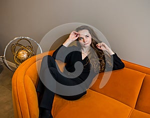 Beautiful young girl posing on a beautiful bright orange sofa photo