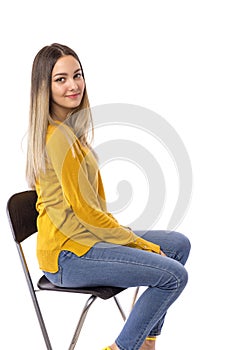 Beautiful young girl posing on a chair over white background