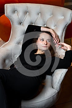 Beautiful young girl posing in a chic white armchair photo