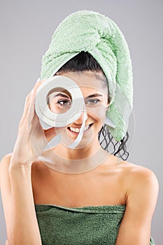 Beautiful young girl posing with towels after having a bath, holding toilet paper role. Smiling face expression