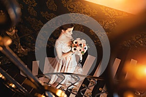 A beautiful young girl in a powdery wedding dress on the background of the interiors of a luxurious historical apartment.