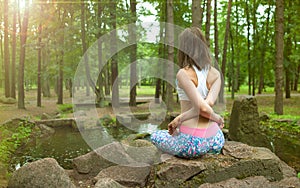 Beautiful young girl practicing yoga and meditation at sunrise in the forest. Shallow depth of field. Balance and spirituality