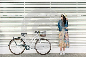 Beautiful young girl with a pretty smile waiting for a friend to take a ride with her bike