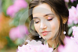 A beautiful young girl with professional makeup plus size in a blooming garden closed her eyes