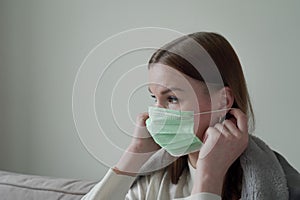 Beautiful young girl puts on a green medical mask on her face. Orvi, coronovirus, acute respiratory infections. photo