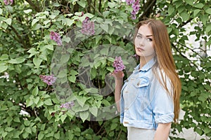 Beautiful young girl with red hair in the garden with lilac