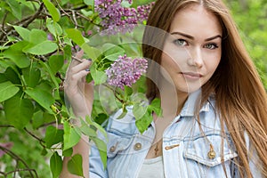 Beautiful young girl with red hair in the garden with lilac