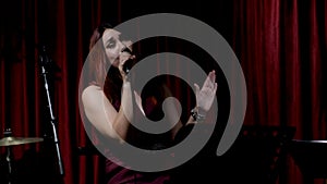 A beautiful young girl with red hair sings while sitting, holding a microphone